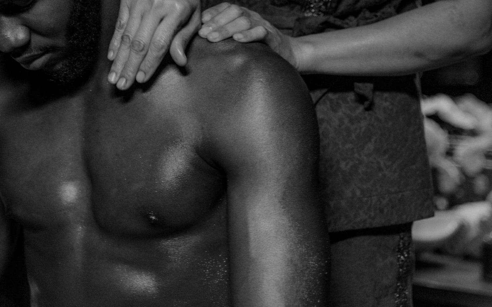 A therapist's hands resting mid-stroke along a draped back
