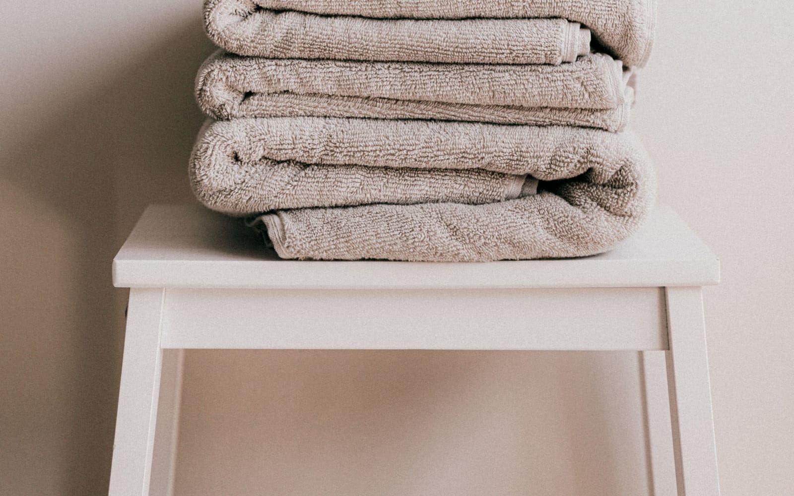 Folded white towels stacked on textured linen in warm, low light