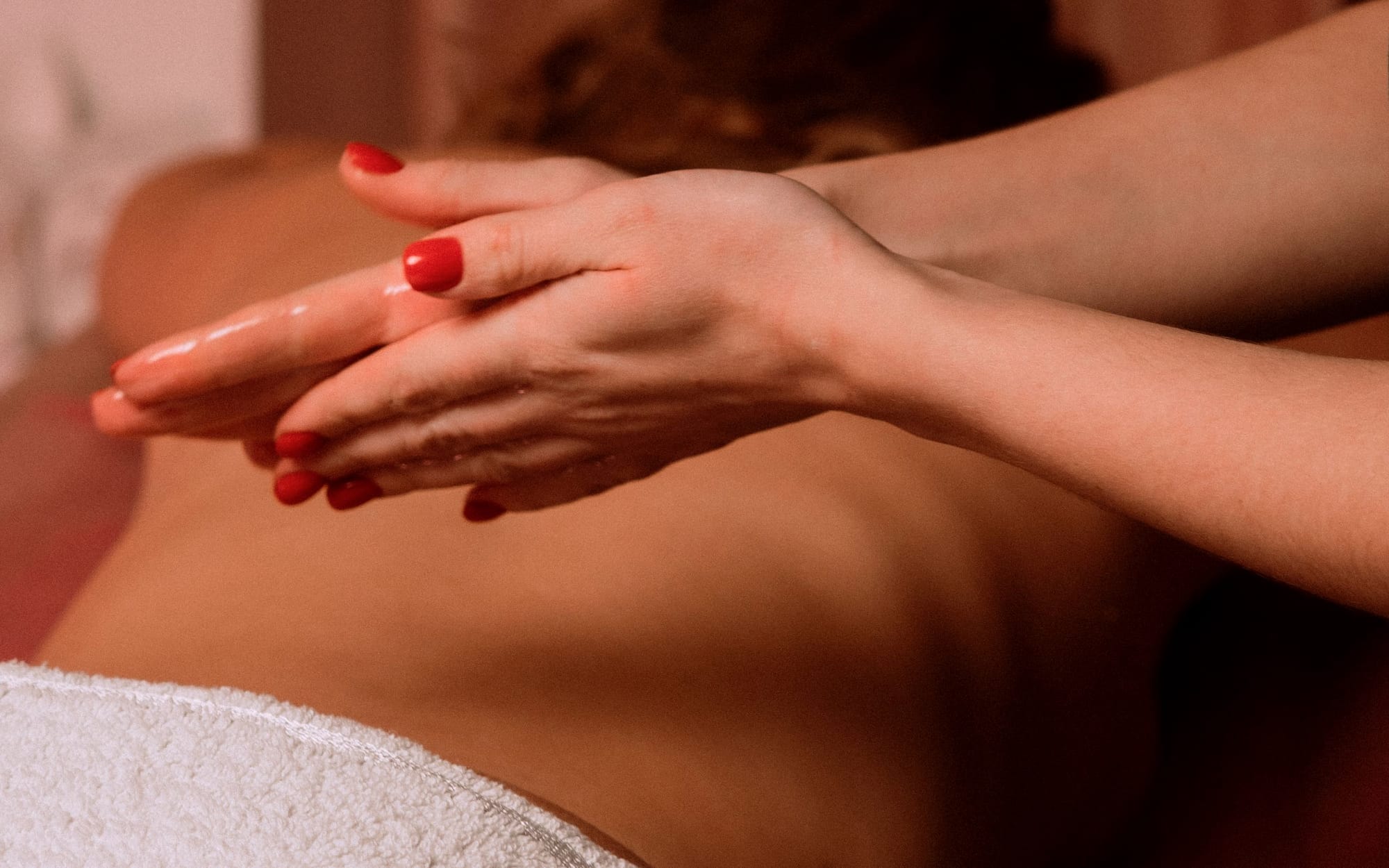 Massage oil warming in a small dish beside a rolled towel